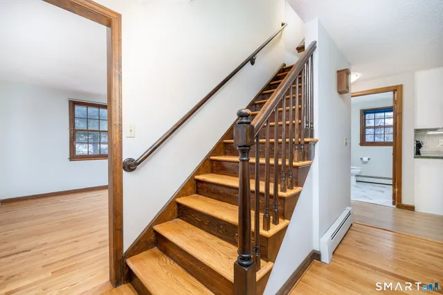 a view of staircase with wooden floor and white walls