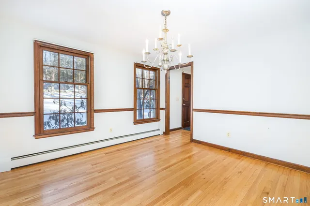 an empty room with wooden floor chandelier and windows