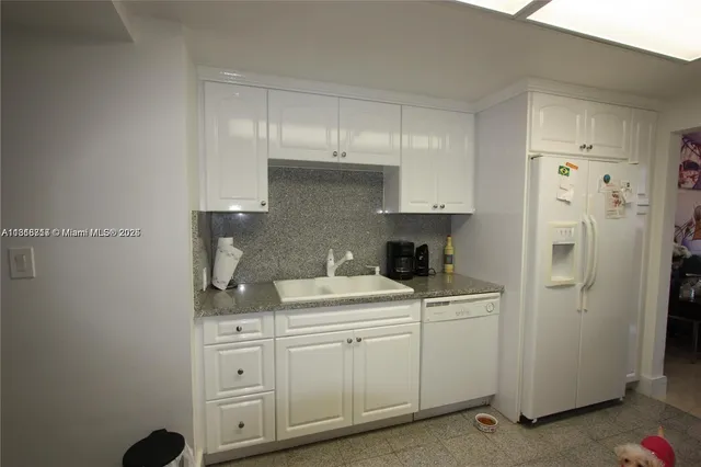 a kitchen with white cabinets sink and refrigerator