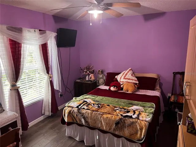 a bedroom with a bed purple white bedspread and pink walls