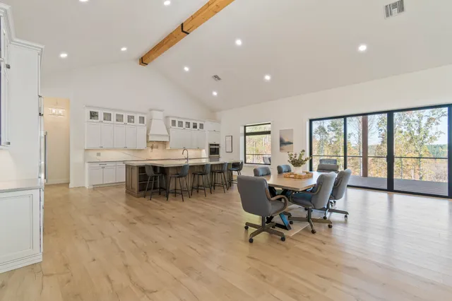 a kitchen with stainless steel appliances kitchen island granite countertop a table chairs sink and cabinets