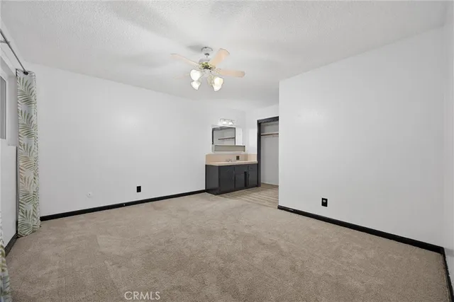 an empty room with chandelier fan and windows