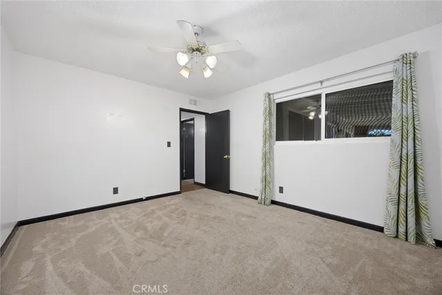 a view of an empty room with a chandelier fan