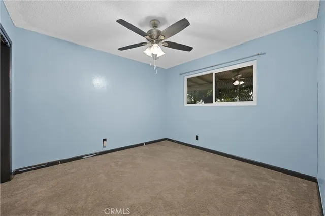 an empty room with ceiling fan and window