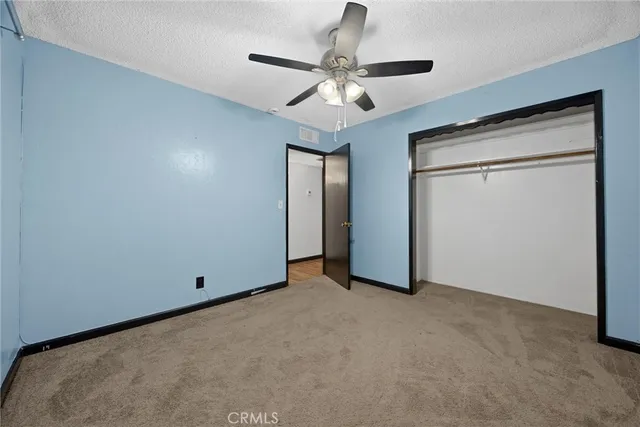 an empty room with closet and a chandelier fan