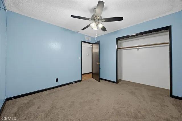 an empty room with closet and a chandelier fan