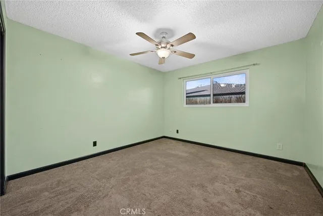 an empty room with windows and fan