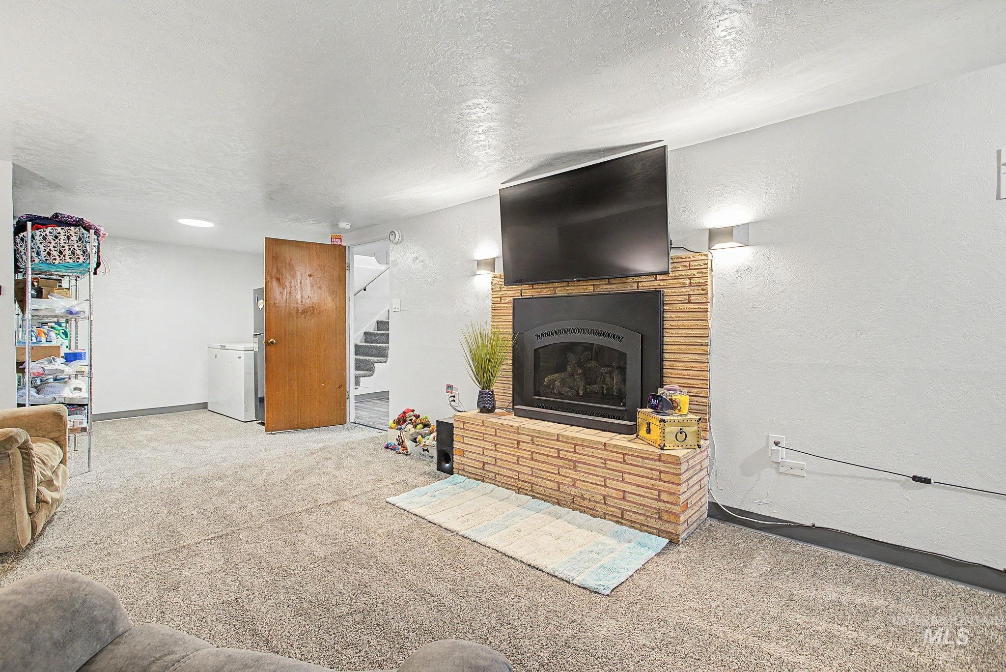 809 Bryden Avenue Lewiston, ID 83501 - Photo 24 of 42 Living area featuring carpet flooring, a textured ceiling, a brick fireplace, and a textured wall
