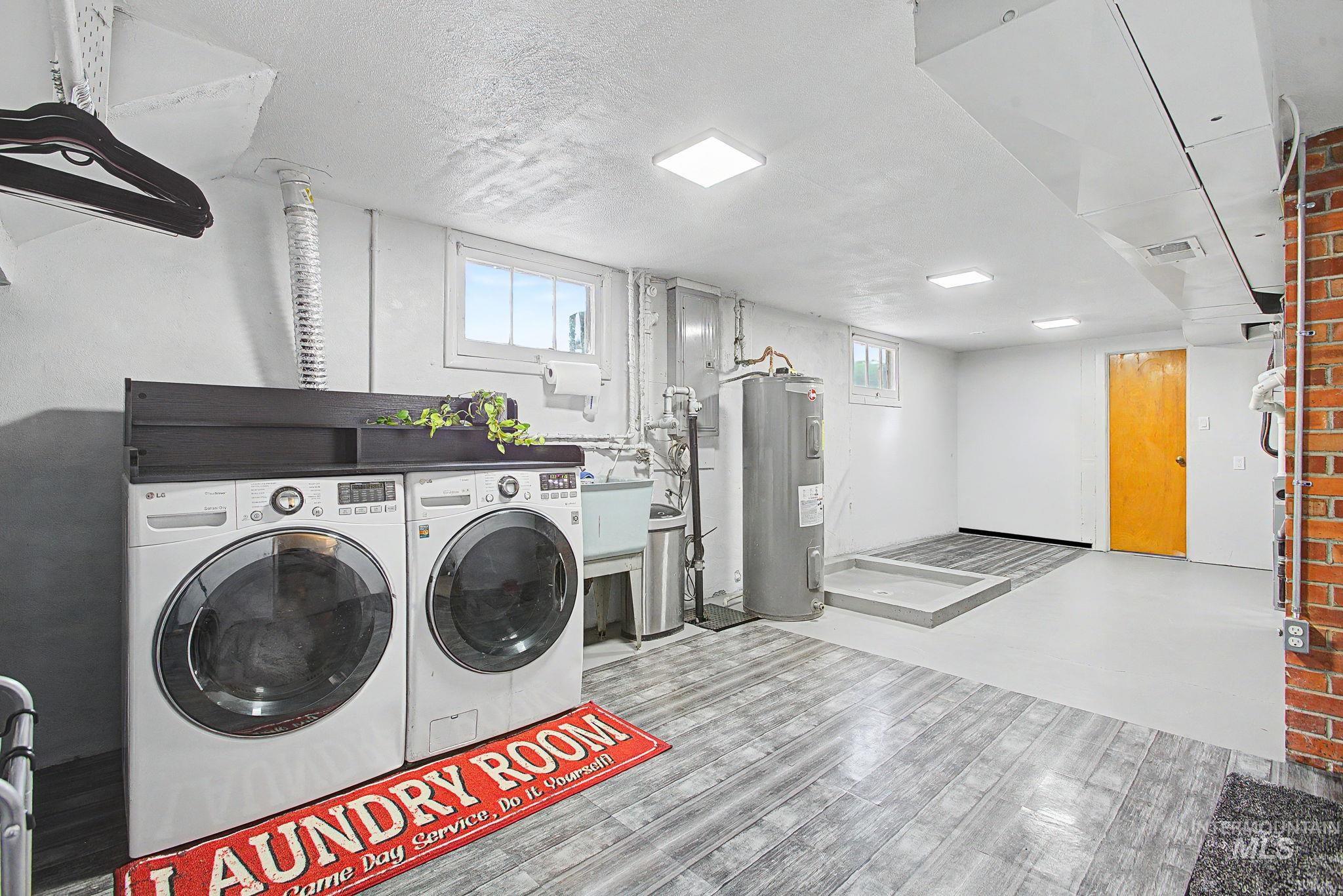 809 Bryden Avenue Lewiston, ID 83501 - Photo 25 of 42 Laundry area featuring electric water heater, washing machine and clothes dryer, a textured ceiling, and light wood-type flooring