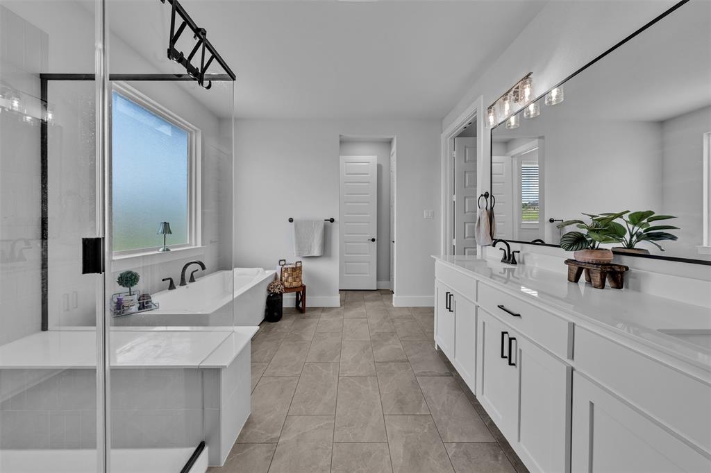 2004 Willy Dilly Road Springtown, TX 76082 - Photo 27 of 40 Spacious bathroom with a walk-in shower featuring a built-in bench, a separate soaking tub, a long double vanity with white cabinetry and dark hardware, a large wall-mounted mirror, and tile flooring