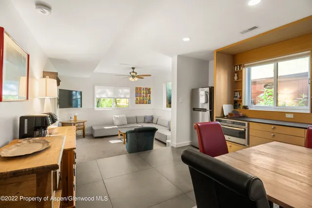 a living room with furniture a large window with kitchen view
