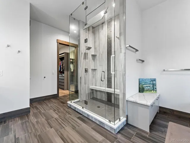 a bathroom with a glass shower door a sink and a mirror