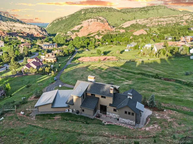 a view of a big house with a big yard plants and large trees