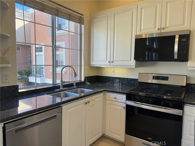 a kitchen with stainless steel appliances granite countertop white cabinets and a granite counter tops