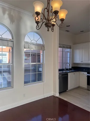 a kitchen with a chandelier and wooden floors