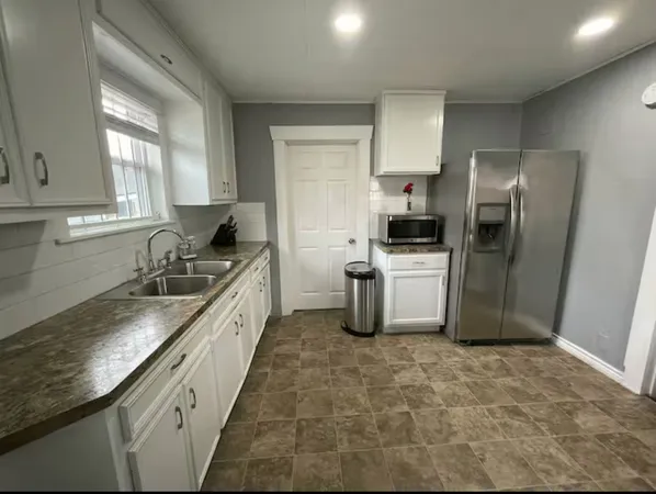 a large kitchen with a granite countertop sink and stainless steel appliances