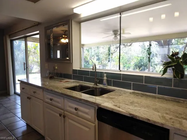 a large open kitchen with granite countertop a sink a counter top space and stainless steel appliances