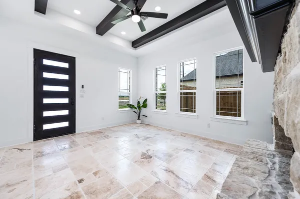 a view of an empty room with a window and kitchen view