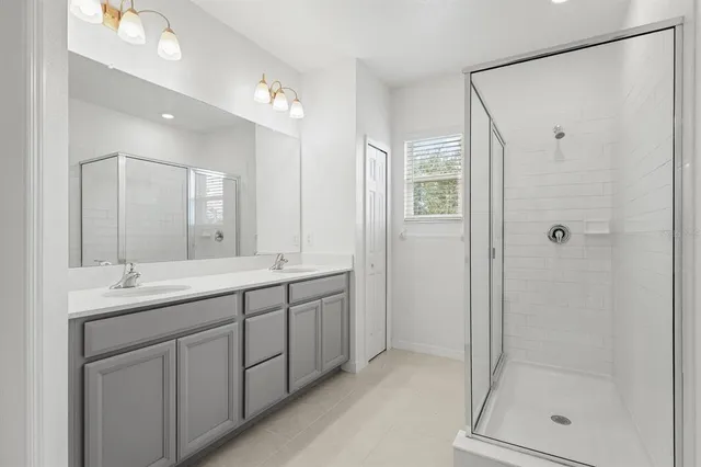 a bathroom with a double vanity sink mirror and shower