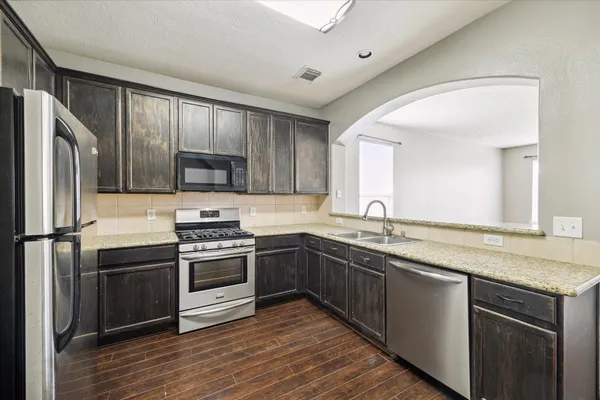 a kitchen with stainless steel appliances granite countertop a sink stove and refrigerator