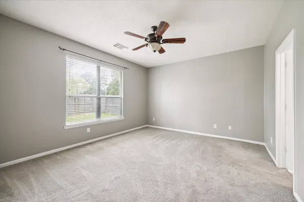 an empty room with a window and a ceiling fan
