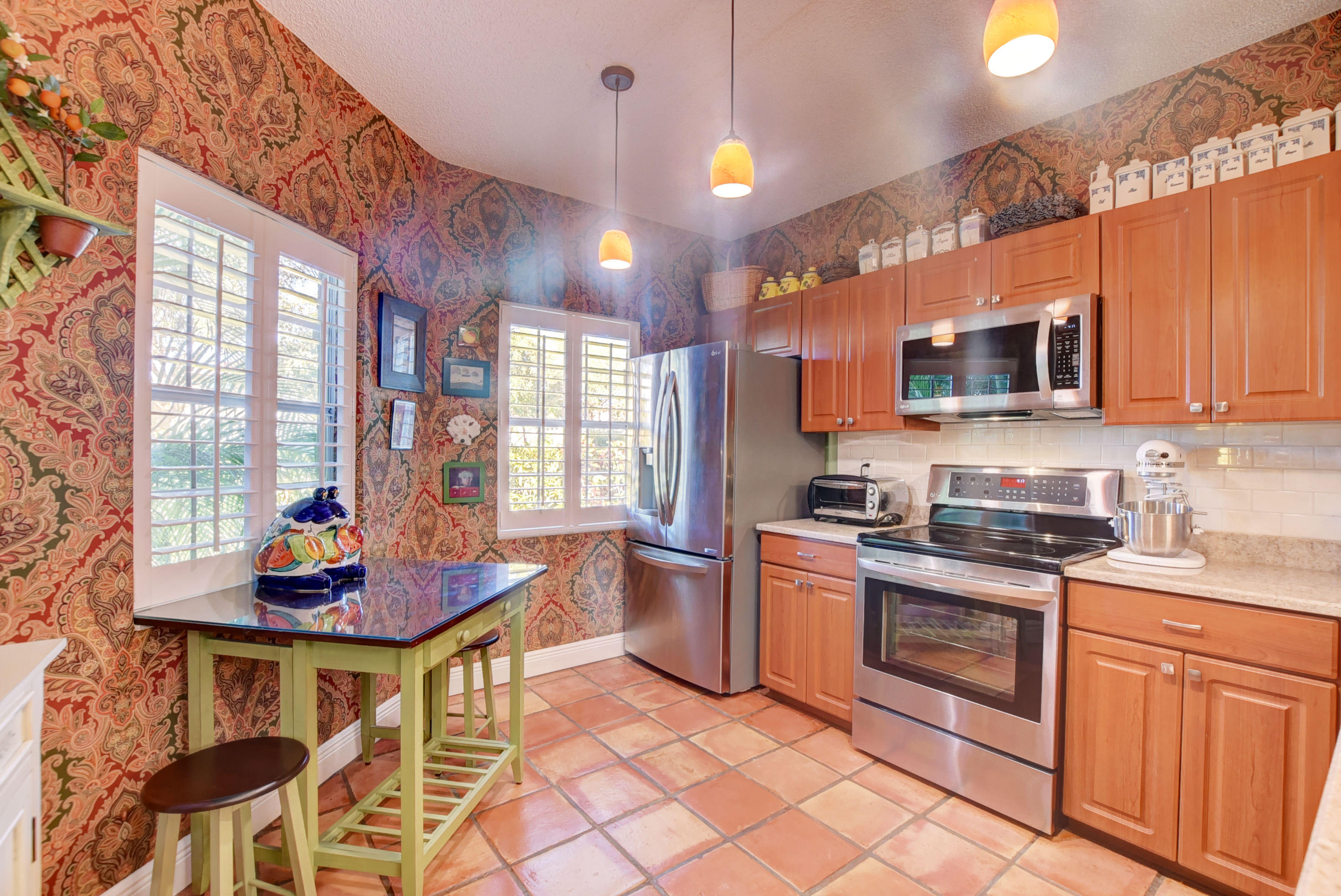 6660 Via Regina Boca Raton, FL 33433 - Photo 12 of 28 a kitchen with stainless steel appliances granite countertop a stove a sink dishwasher and a microwave oven with a dining table