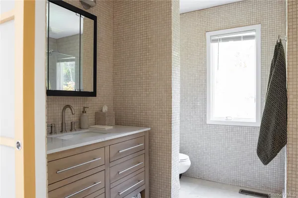 a bathroom with a granite countertop sink toilet and mirror