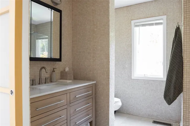 a bathroom with a granite countertop sink toilet and mirror