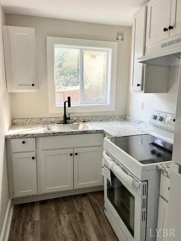 a kitchen with granite countertop a sink cabinets stainless steel appliances and a window