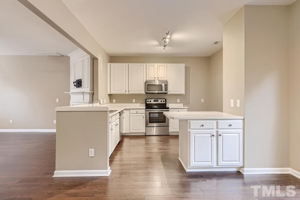 8155 Rhiannon Road Raleigh, NC 27613 - Photo 8 of 27 a kitchen with granite countertop white cabinets and white appliances