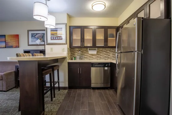 a kitchen with stainless steel appliances granite countertop a refrigerator a sink a stove and a wooden floors