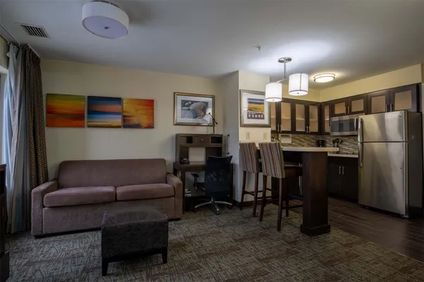 a living room with furniture and a dining table with kitchen appliances