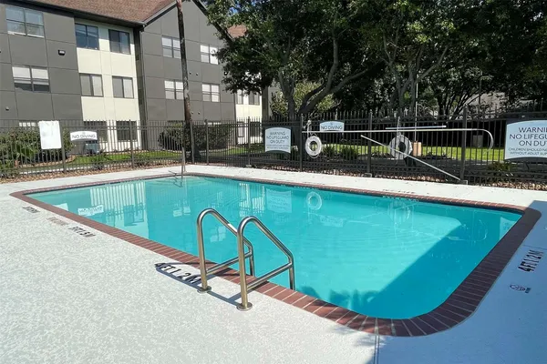 a view of a swimming pool with a bench and trees in the background