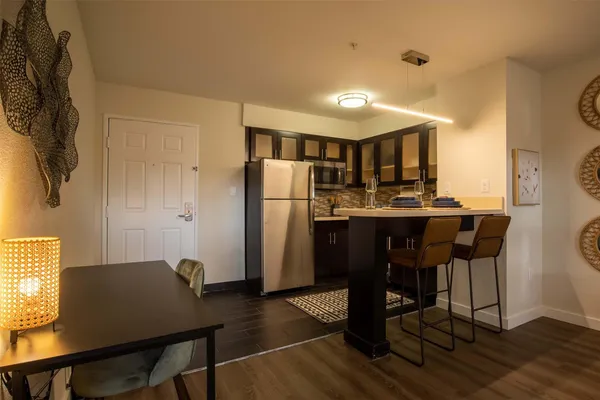 a kitchen with stainless steel appliances a table chairs and a refrigerator