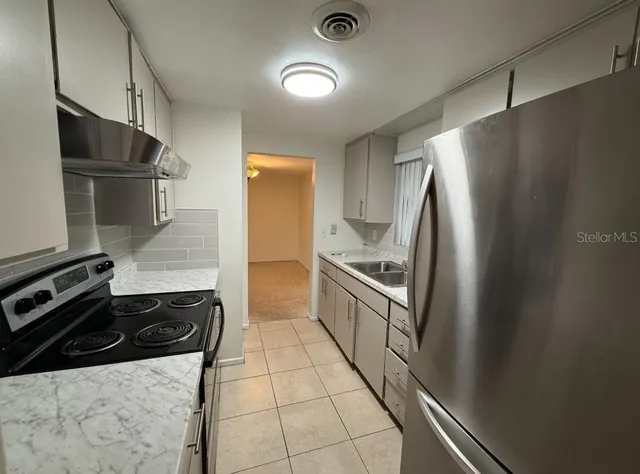 a kitchen with granite countertop a refrigerator and a sink