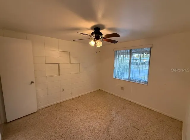 an empty room with windows and fan