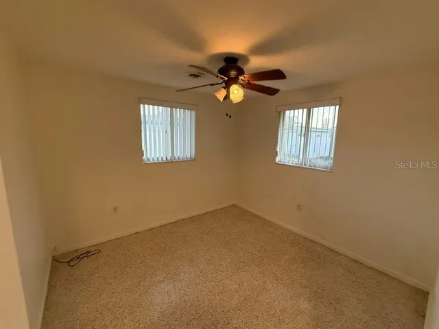 an empty room with windows and fan