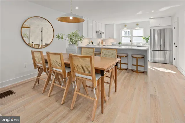 a kitchen with stainless steel appliances granite countertop a table chairs refrigerator and sink