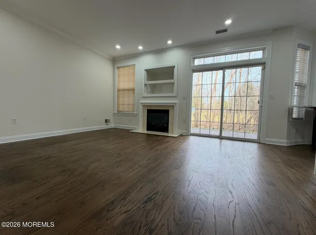 an empty room with wooden floor fireplace and windows