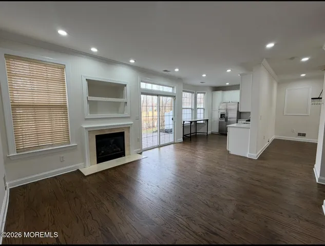 a view of an empty room with wooden floor and a kitchen
