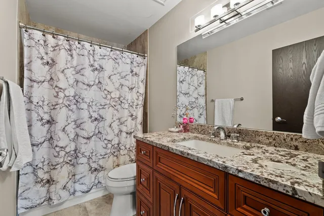 a bathroom with a granite countertop sink a toilet and a mirror