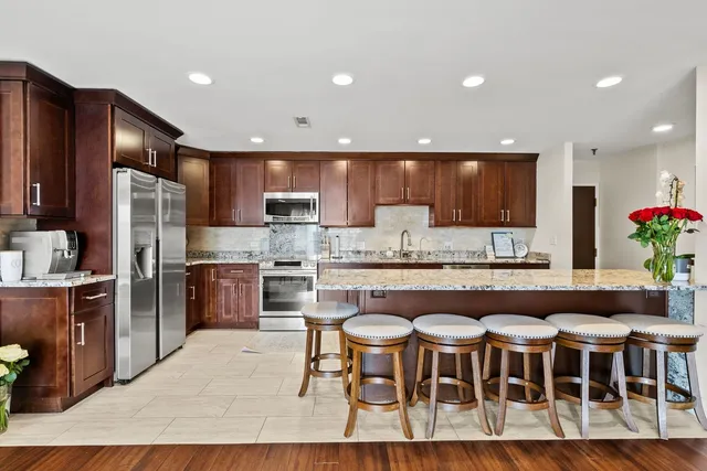 a kitchen with stainless steel appliances granite countertop a table chairs sink refrigerator and microwave
