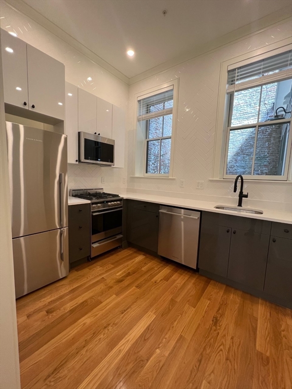 a kitchen with stainless steel appliances a sink cabinets and a wooden floor