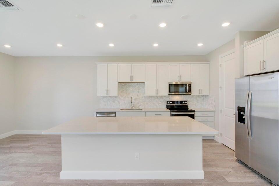 1875 Southeast Ocean Cove Way Stuart, FL 34996 - Photo 6 of 37 a kitchen with stainless steel appliances a refrigerator a stove a microwave and white cabinets
