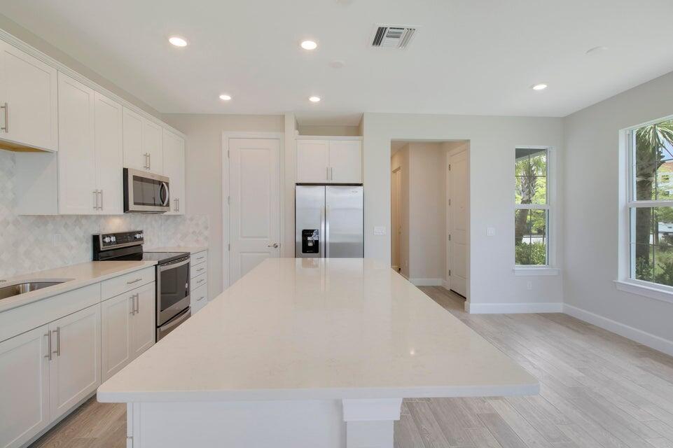 1875 Southeast Ocean Cove Way Stuart, FL 34996 - Photo 9 of 37 a large white kitchen with white cabinets and wooden floor