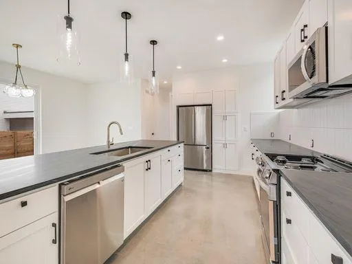 a kitchen with stainless steel appliances granite countertop a sink a stove and a refrigerator