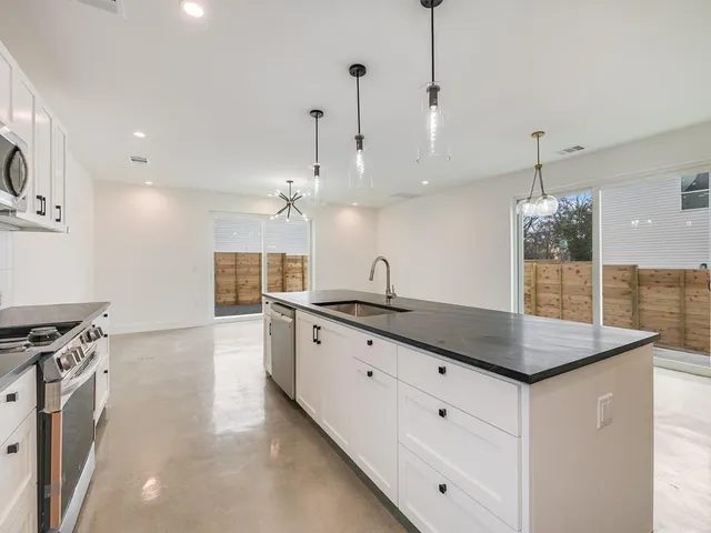 a kitchen with granite countertop a sink a counter space appliances and cabinets