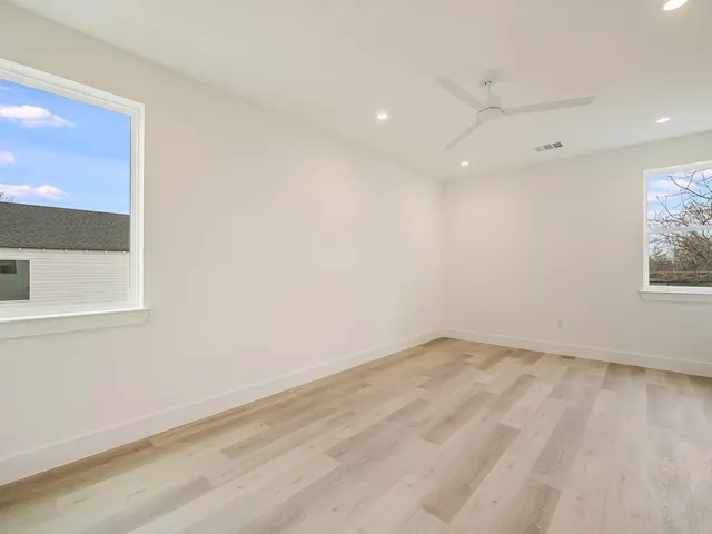 an empty room with wooden floor and windows