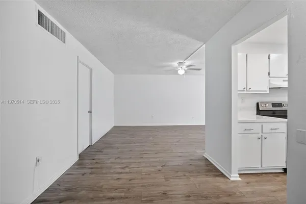 a view of a kitchen with white cabinets and wooden floor