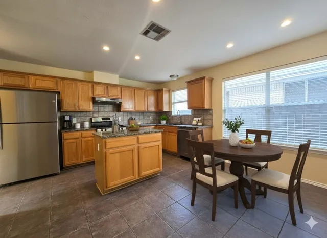 a kitchen with granite countertop a table chairs stainless steel appliances and cabinets